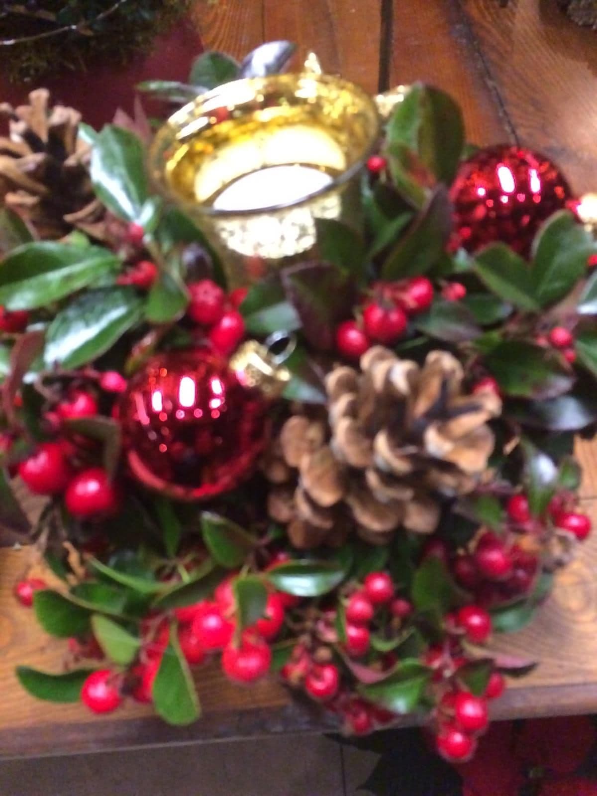 Adventsgesteck mit Zapfen, roten Kugeln und Windlicht