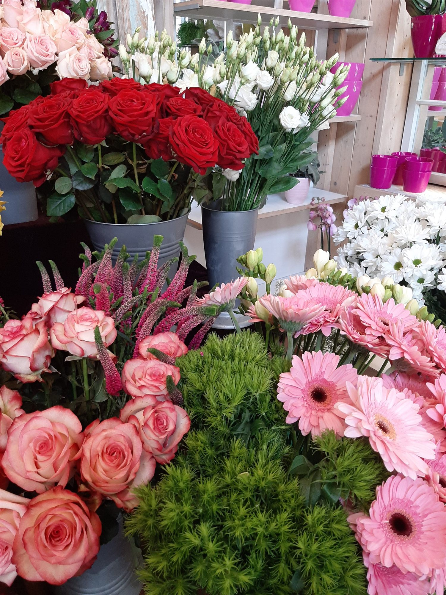 Rote Rosen und gebundene Sträuße vor den Regalen im Verkaufsraum