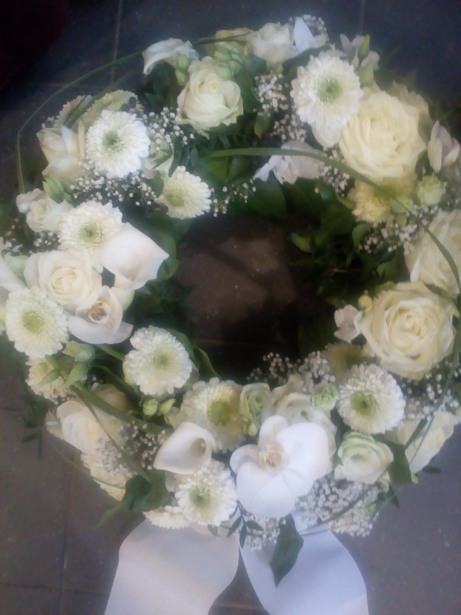 Runder weißer Trauerkranz aus Rosen, Calla und Chrysanthemen mit weißer Schleife