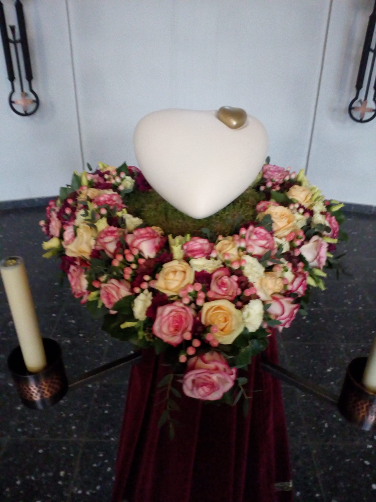 Herzförmiger Urnenschmuck mit Rosen in Apricot und Rosé, aufgebahrt in der Trauerhalle